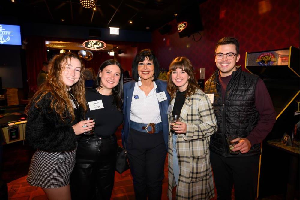 Four alumni standing with President Mantella at the event.